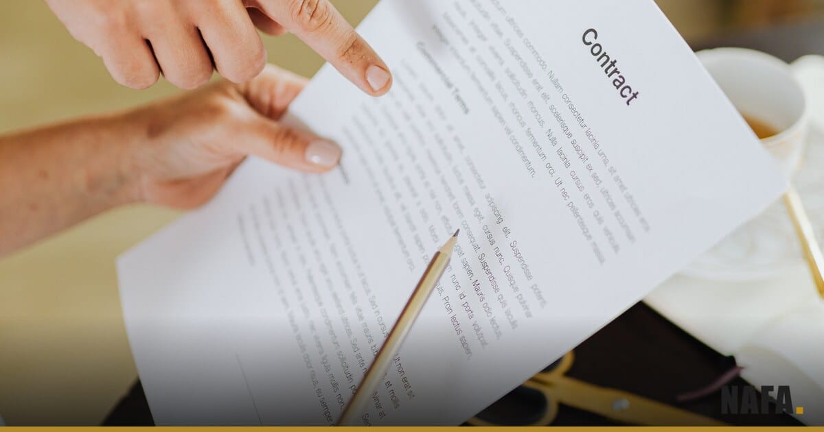 Des mains classent des documents à côté d'un ordinateur portable.