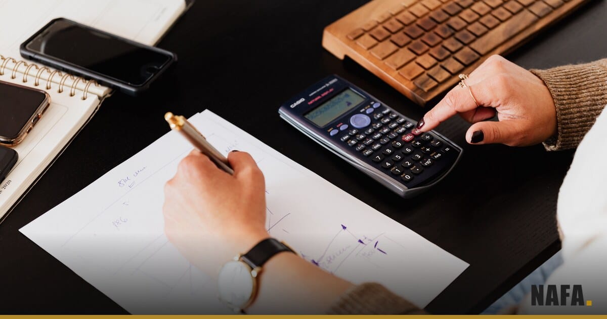 Des mains utilisant une calculatrice et un carnet pour vérifier un montant de dividende.