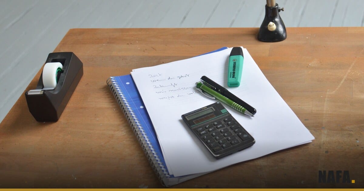 Dossier papier, stylo et calculatrice disposés sur un bureau