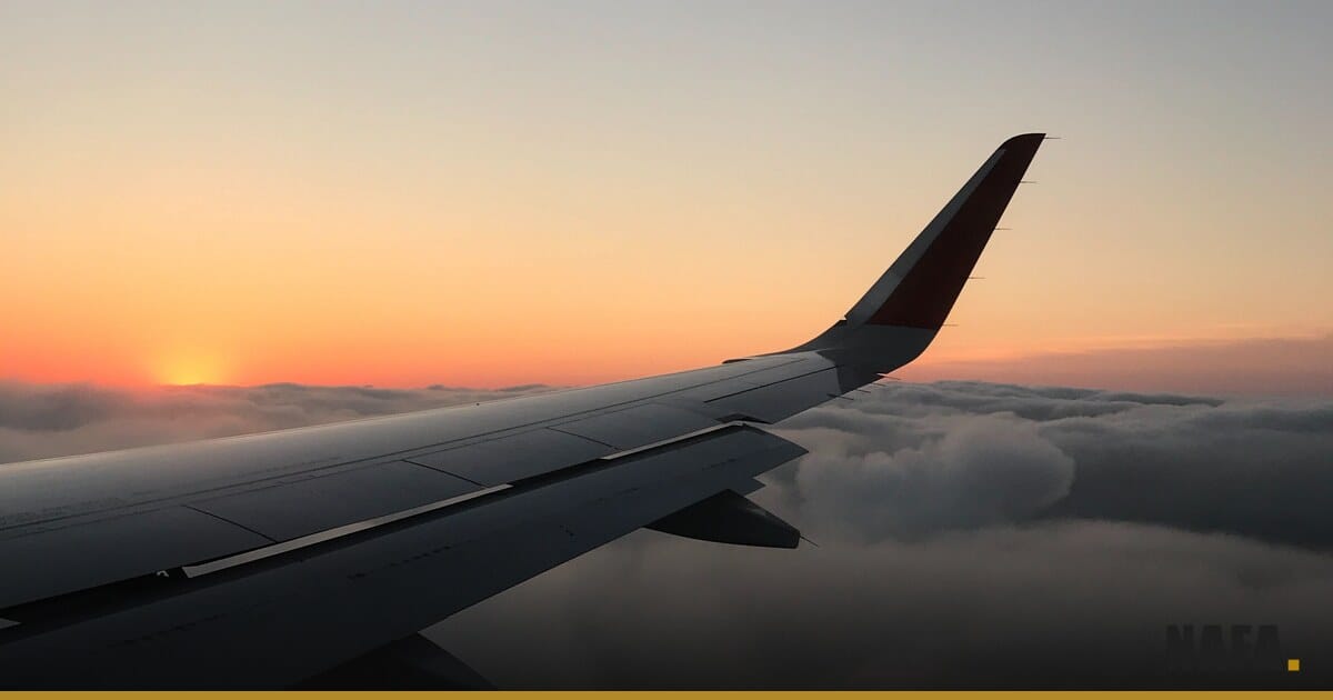 Aile d'avion au coucher de soleil au-dessus des nuages