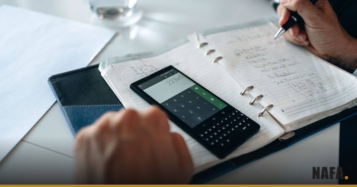 Carnet, calculatrice et téléphone posés sur une table pour examiner un budget.