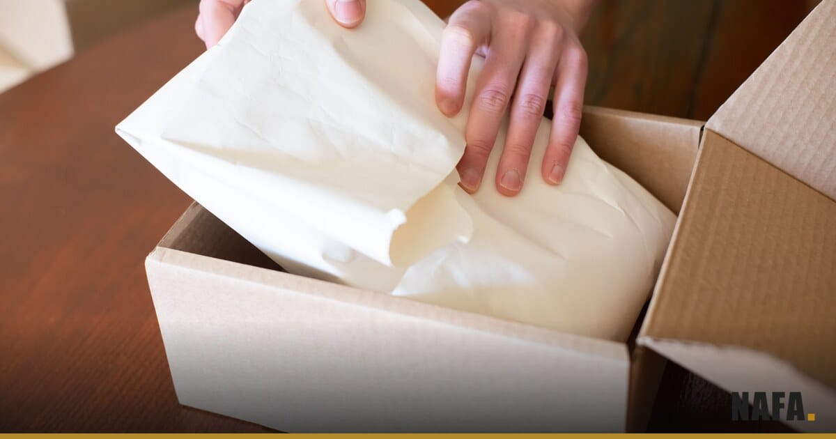 Mains contrôlant des articles dans un carton à côté d'une calculatrice sur un comptoir