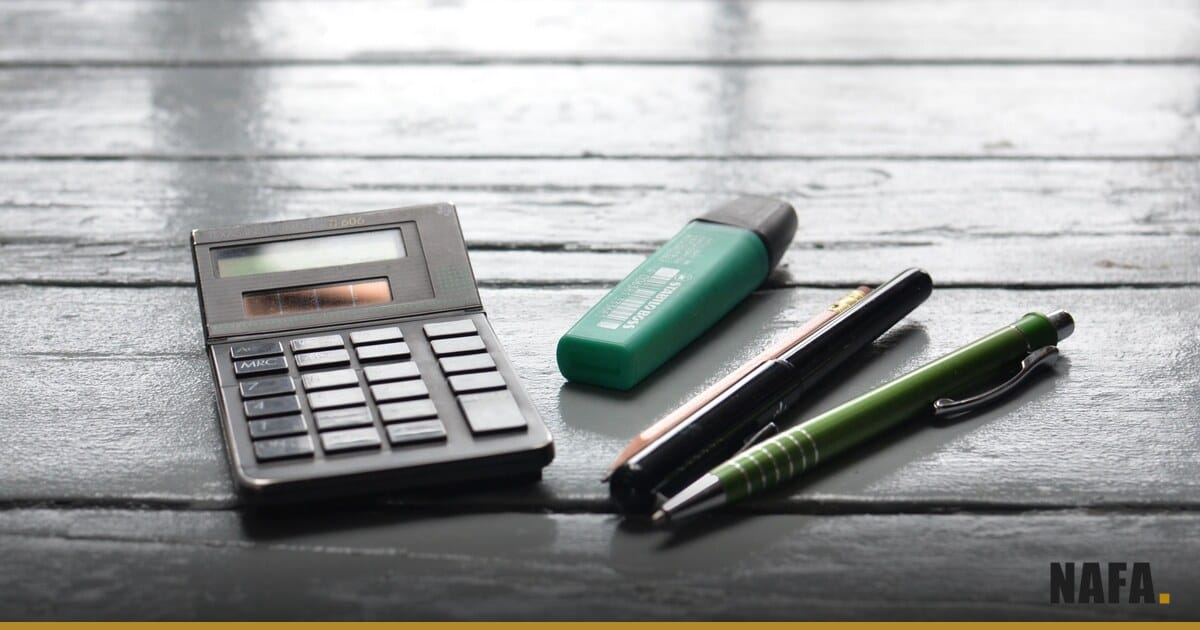 Calculatrice et stylos posés sur un plan de travail, pour le suivi des ventes à crédit.