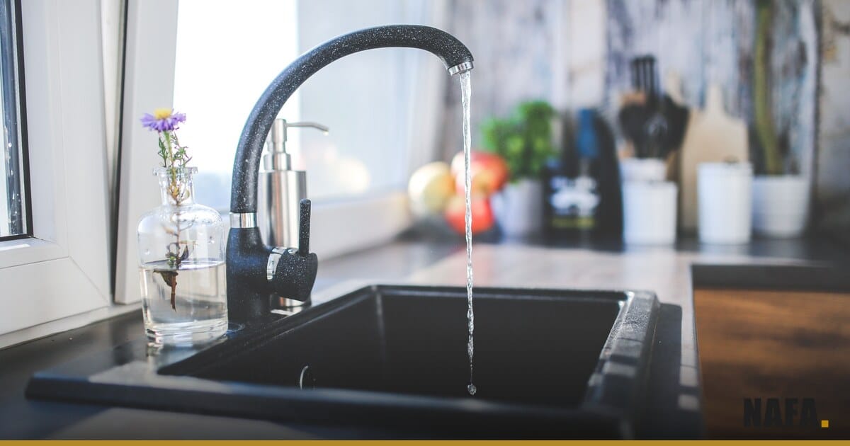 Gros plan sur un robinet domestique au-dessus d'un évier avec de l'eau qui coule.