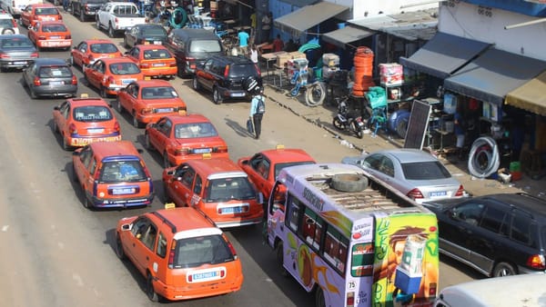 Embouteillage de taxis et de gbakas orange sur une route d'Abidjan