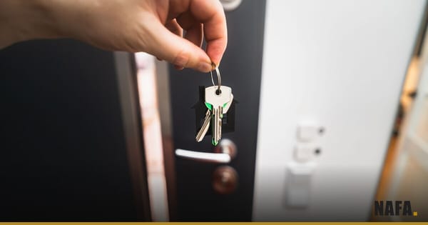 Main tenant des clés devant la porte d'un logement à louer