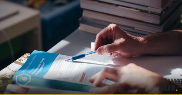 Mains tenant un stylo au-dessus d'un cahier d'école, à côté d'une pile de livres