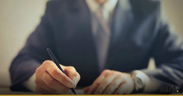 Homme d'affaires signant un document papier, mains en gros plan, visage non visible.