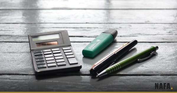 Calculatrice et stylos posés sur un plan de travail, pour le suivi des ventes à crédit.